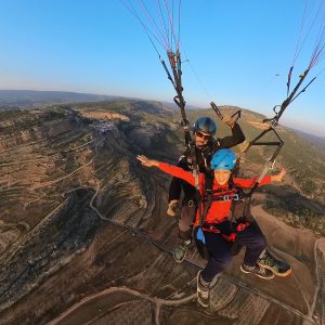 "Niño disfrutando de un vuelo en parapente biplaza sobre su pueblo Alpuente con instructor en la provincia de Valencia"