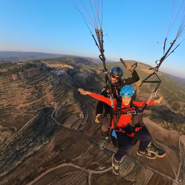 "Niño disfrutando de un vuelo en parapente biplaza sobre su pueblo Alpuente con instructor en la provincia de Valencia"
